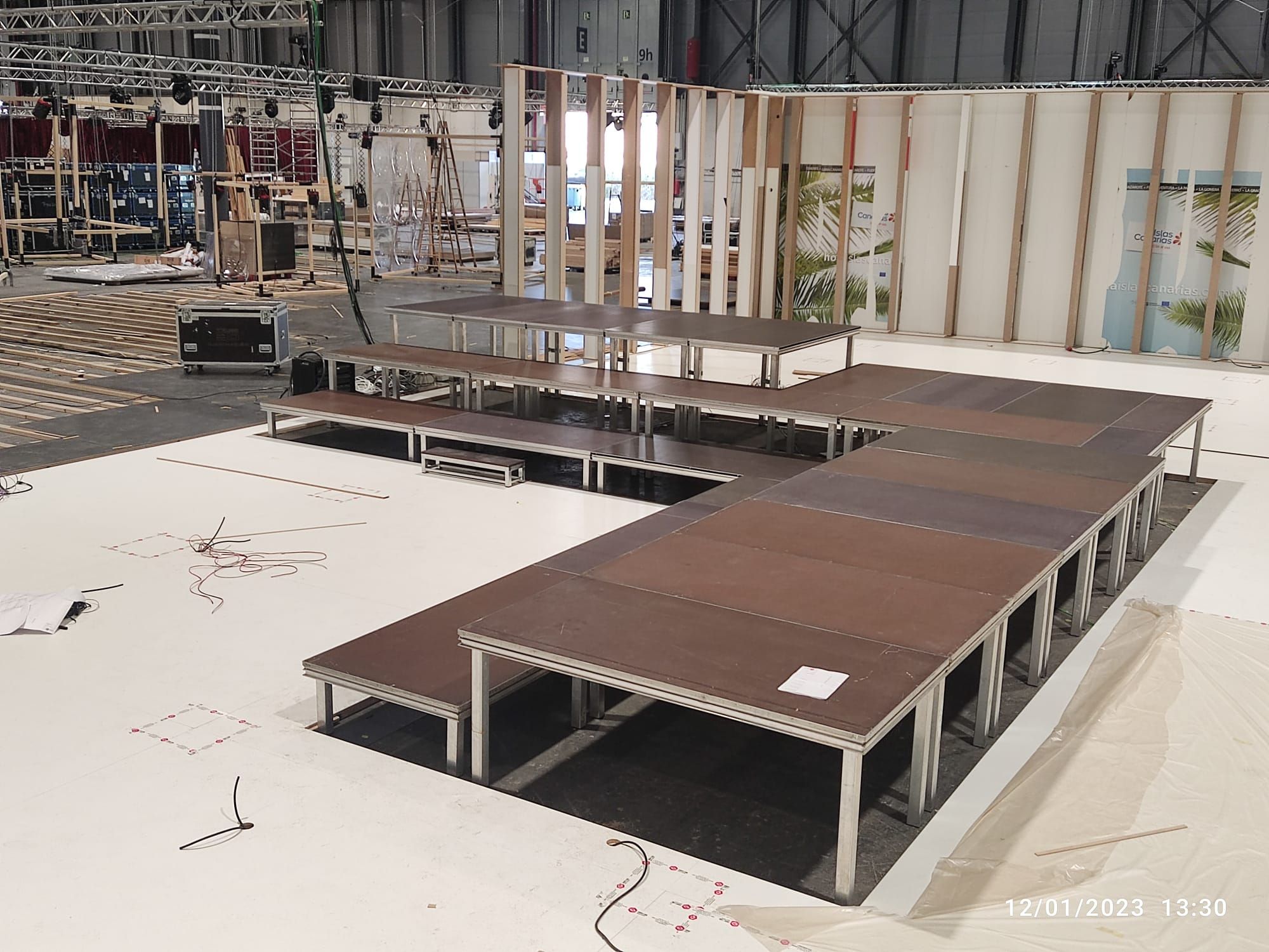 Montaje de tarimas modulares escalonadas en forma de T para feria o desfile en recinto ferial